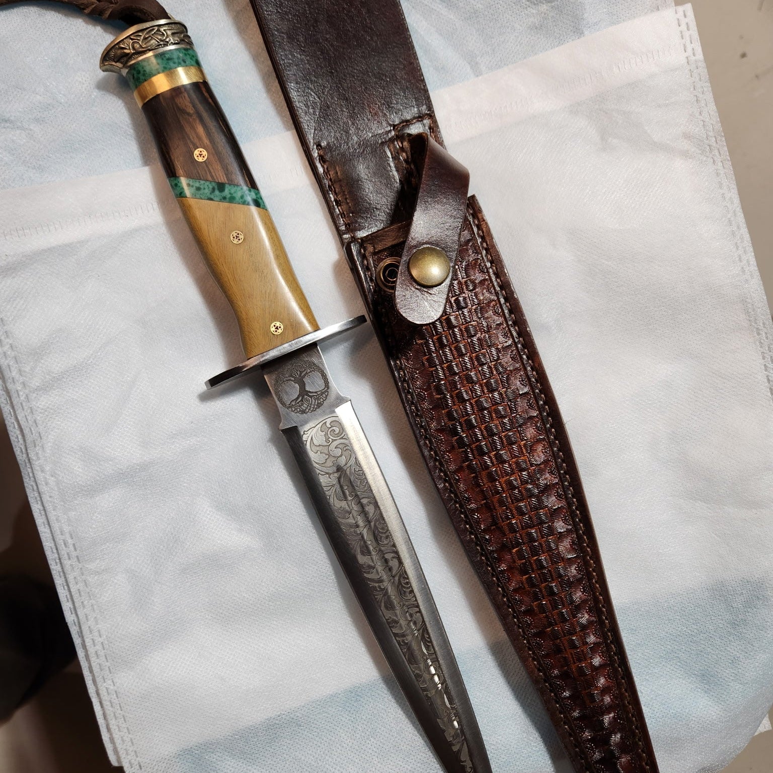 Scottish Dirk Knife with decorative handle and leather sheath on a white cloth background