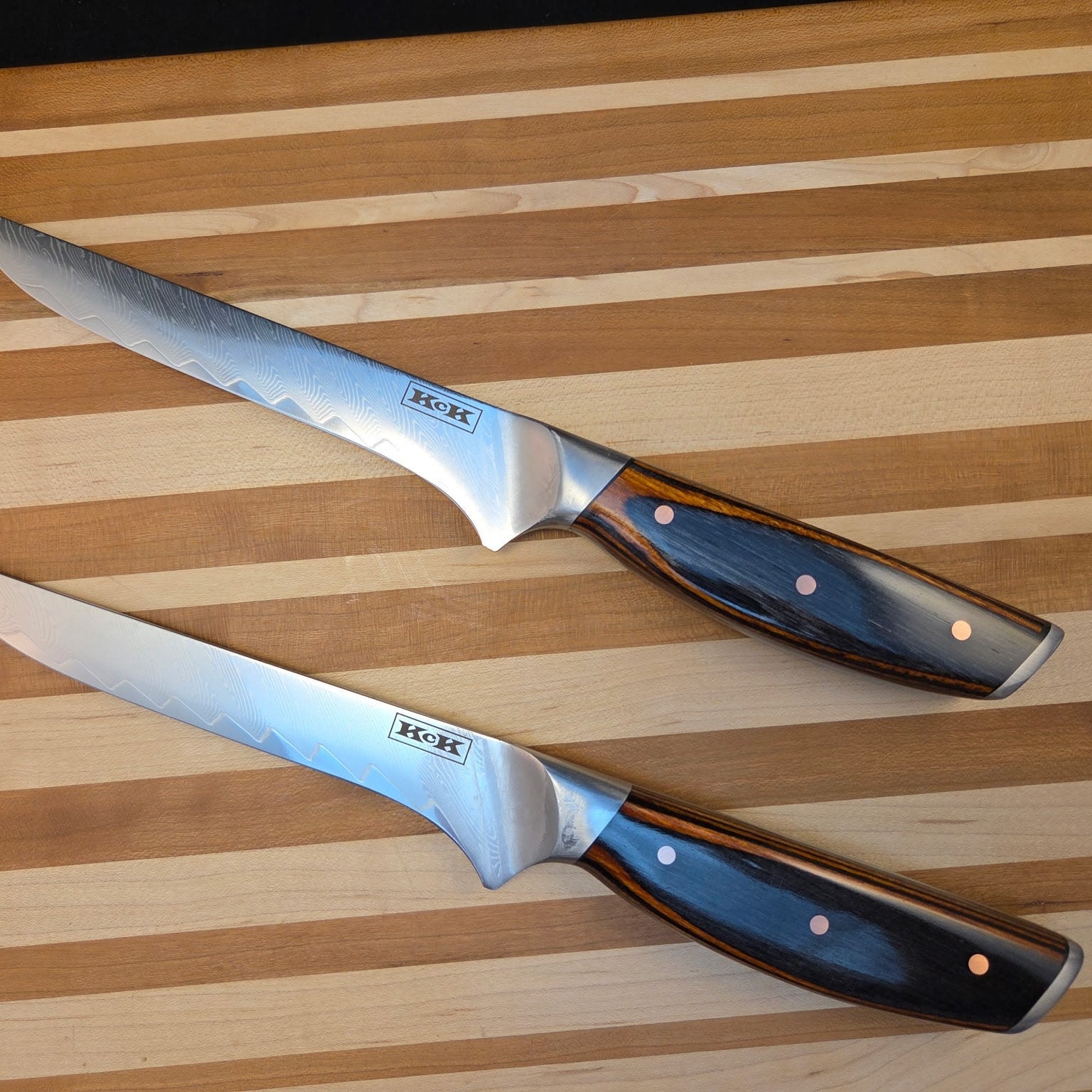 Two boning knives with wooden handles displayed on wooden cutting board